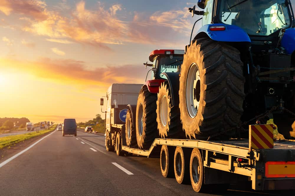 flatbed truck hauling large tractors